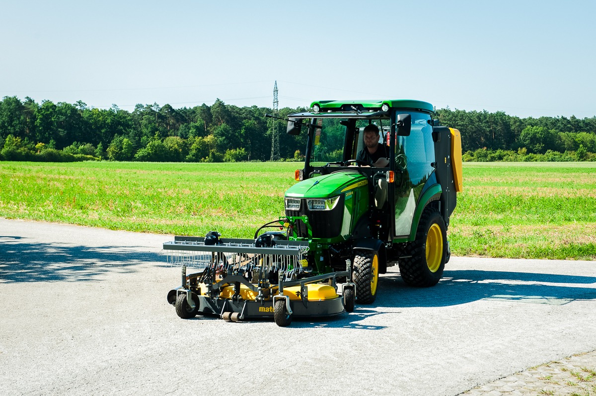John Deere Kompakttraktor mit Frontmähwerk bei Grünflächenpflege auf Asphalt und befestigten Flächen