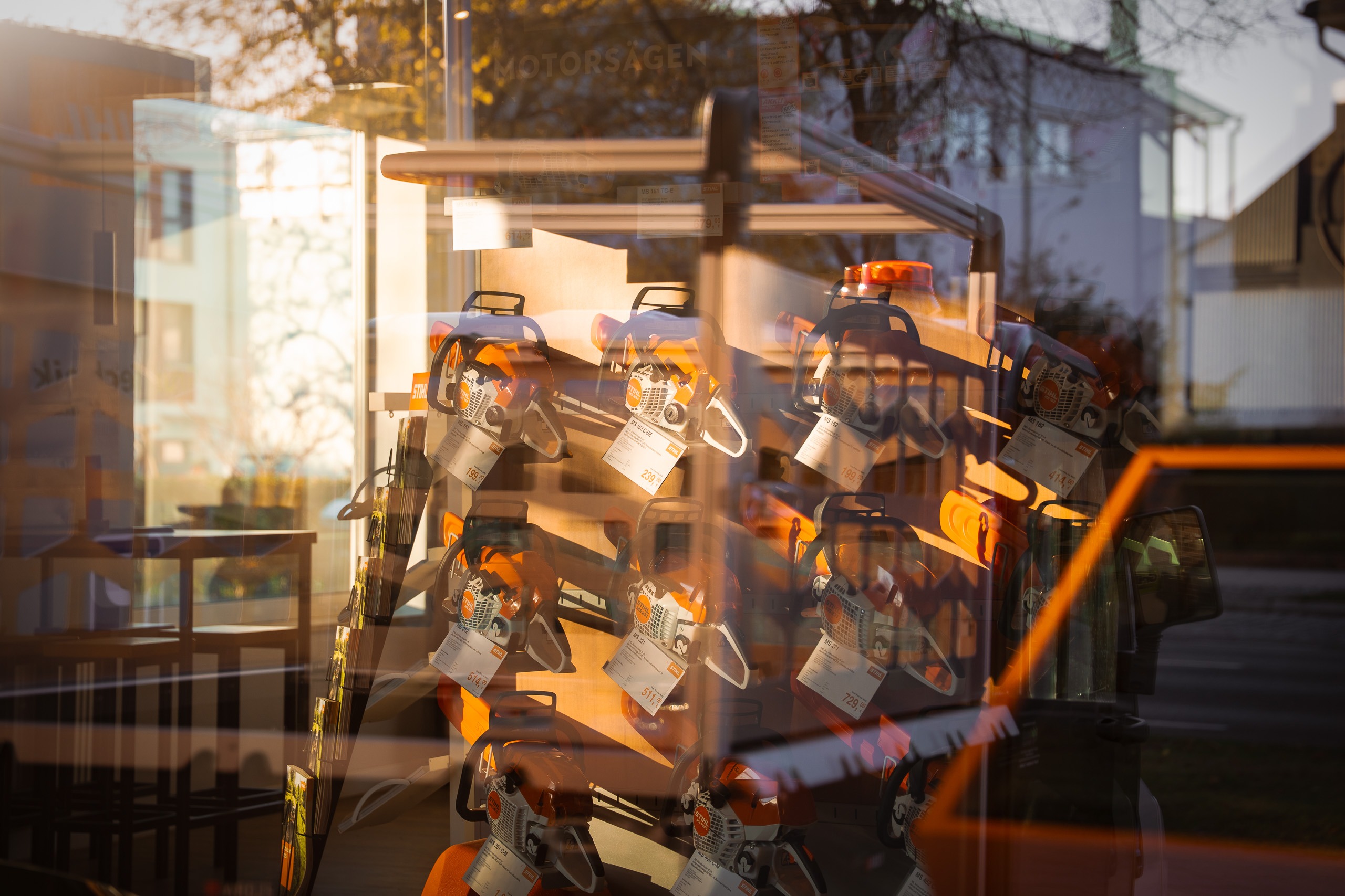 Schaufensteransicht der GrünTechnik Frank GmbH mit einer Auswahl an STIHL Motorsägen auf einem Verkaufsdisplay bei Sonnenuntergang.